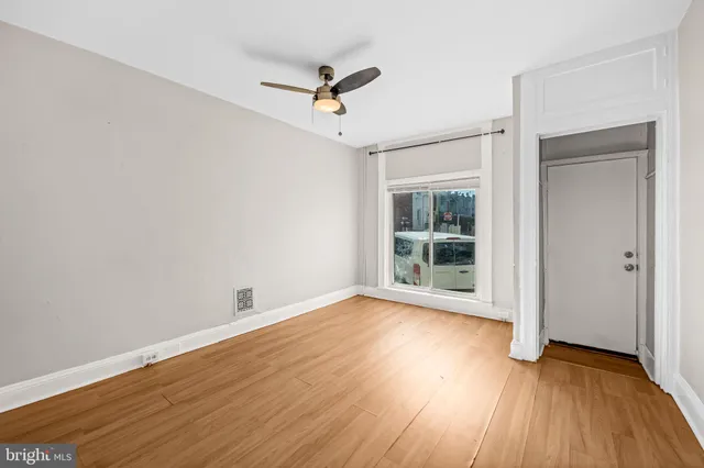an empty room with wooden floor fan and windows