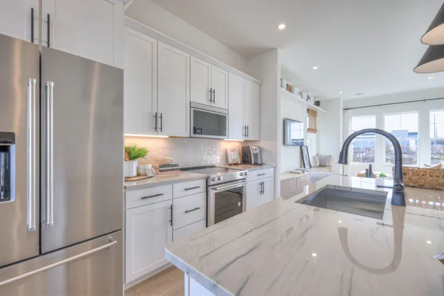 a kitchen with granite countertop white cabinets and stainless steel appliances