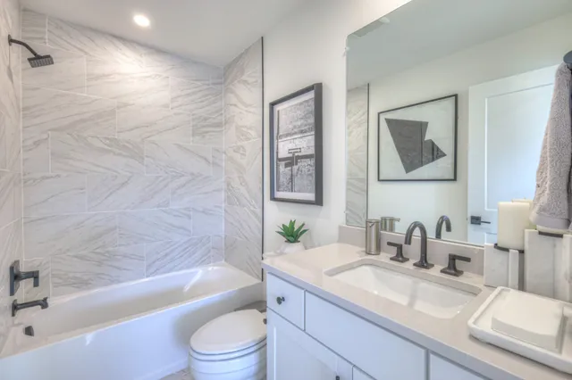 a bathroom with a granite countertop sink a toilet a bathtub and shower
