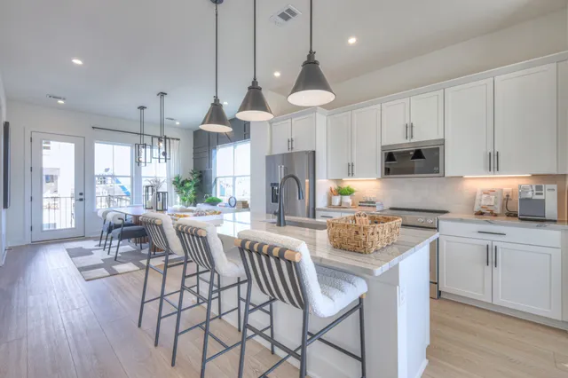 a kitchen with stainless steel appliances a dining table chairs stove and white cabinets