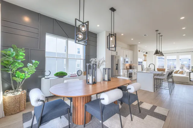 a open dining room with furniture a chandelier and wooden floor