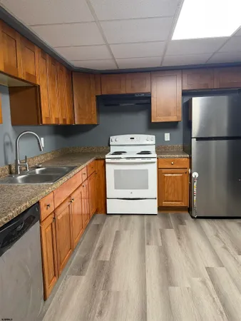 a kitchen with stainless steel appliances granite countertop a sink a stove a refrigerator with grey cabinets and wooden floor