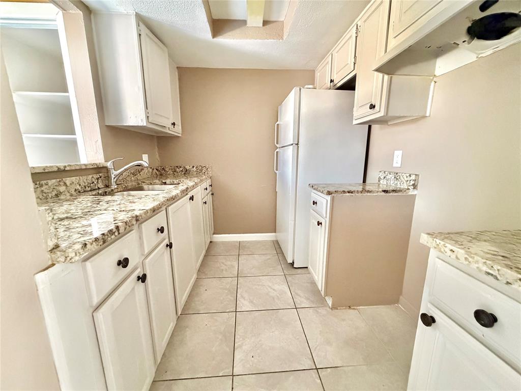 8001 Rothington Road, Unit 33 Dallas, TX 75227 - Photo 4 of 15 Kitchen featuring light-toned cabinetry with dark hardware, granite-style countertops, an undermount sink, and tiled flooring