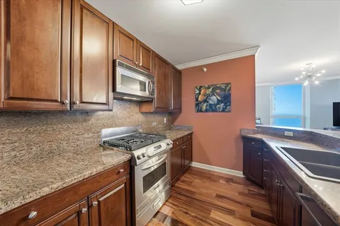 a kitchen with granite countertop stainless steel appliances a stove top oven and sink