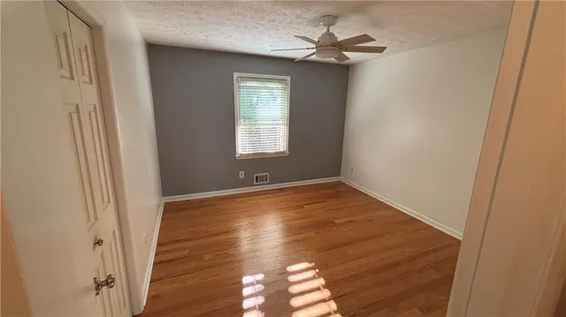 a view of empty room with wooden floor and fan