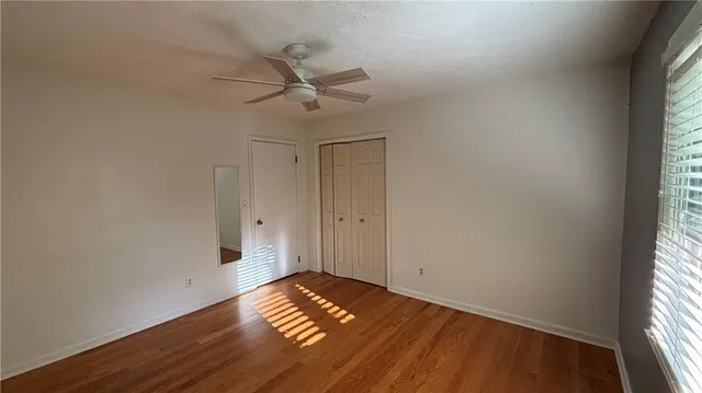 a view of empty room with wooden floor and fan