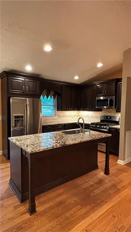 a kitchen with stainless steel appliances granite countertop a stove and a wooden cabinets