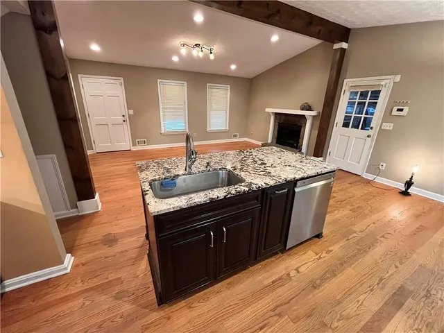 a kitchen with stainless steel appliances granite countertop a sink stove and wooden floor