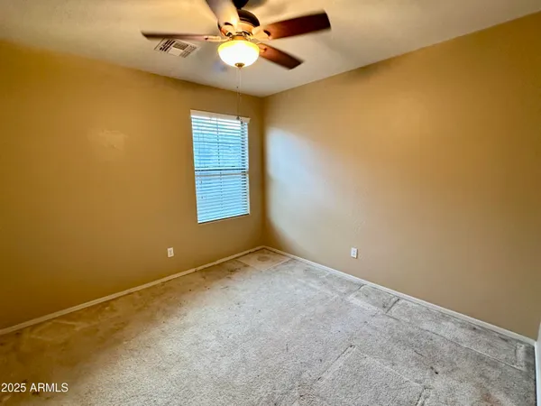 an empty room with windows and fan