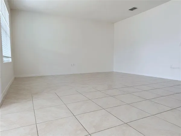 an empty room with chandelier fan and windows