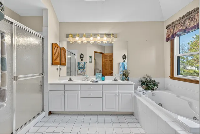 a bathroom with a bathtub a sink a mirror and a shower