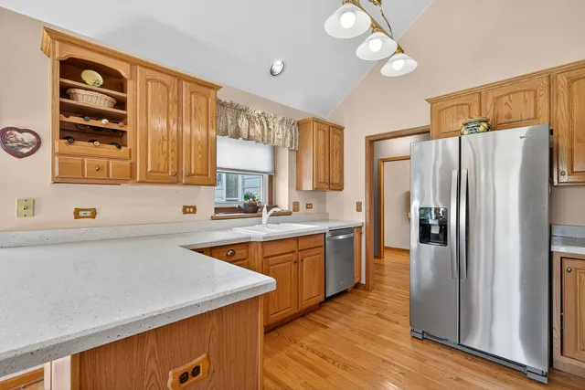 a kitchen with stainless steel appliances a refrigerator a sink and wooden cabinets