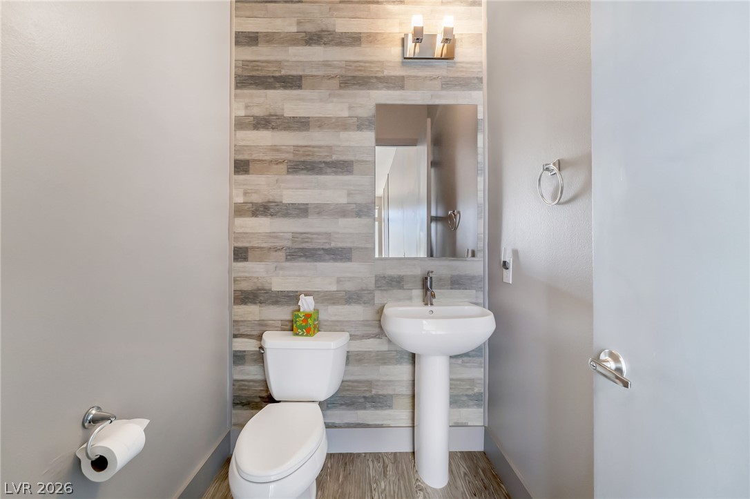 2775 West Pebble Road, Unit 505 Las Vegas, NV 89123 - Photo 8 of 26 A compact and functional lavatory with wood-look tiled accent wall and pedestal sink.