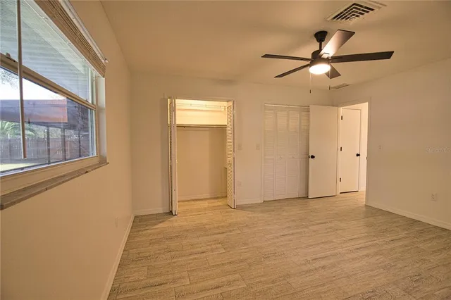 a view of empty room with wooden floor and fan