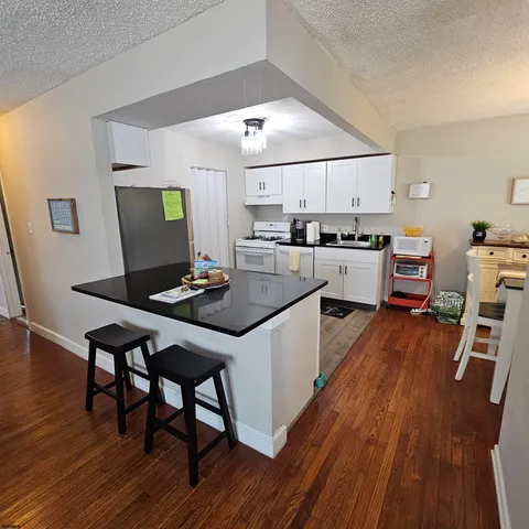 a kitchen with a dining table chairs and wooden floor