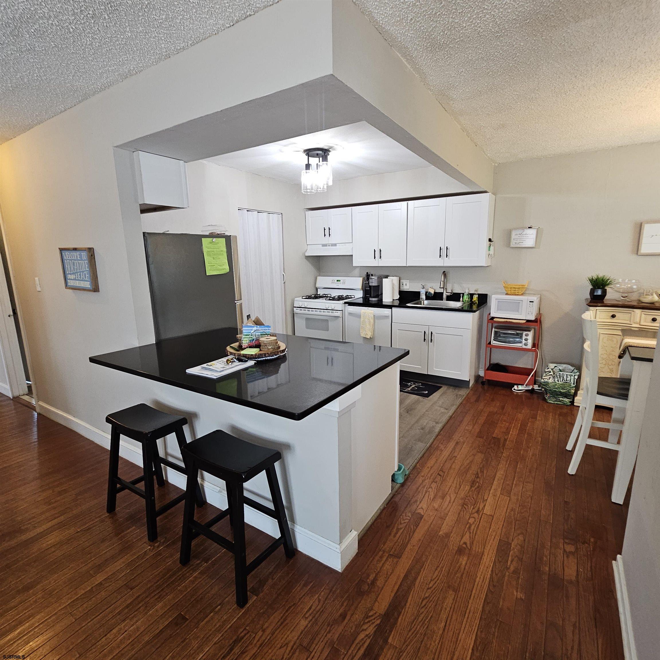 518 Casa Drive, Unit SUMMER RENTAL Brigantine, NJ 08203 - Photo 9 of 19 a kitchen with a dining table chairs and wooden floor