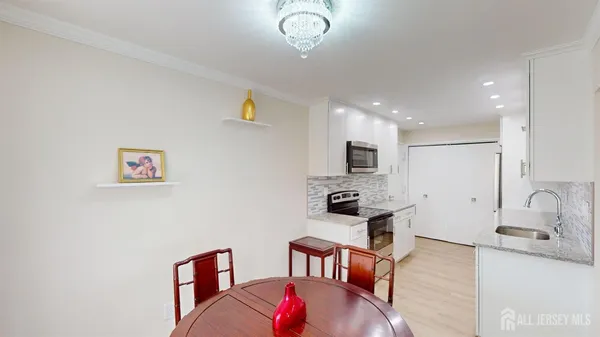 a living room with stainless steel appliances furniture a rug and a kitchen view