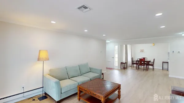 a living room with furniture and a dining table with wooden floor