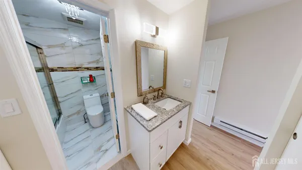 a bathroom with a granite countertop sink toilet and shower a mirror