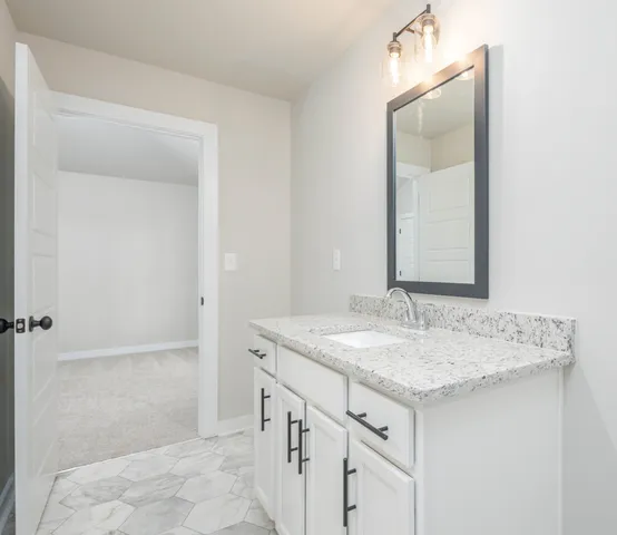 a bathroom with a granite countertop sink and a mirror