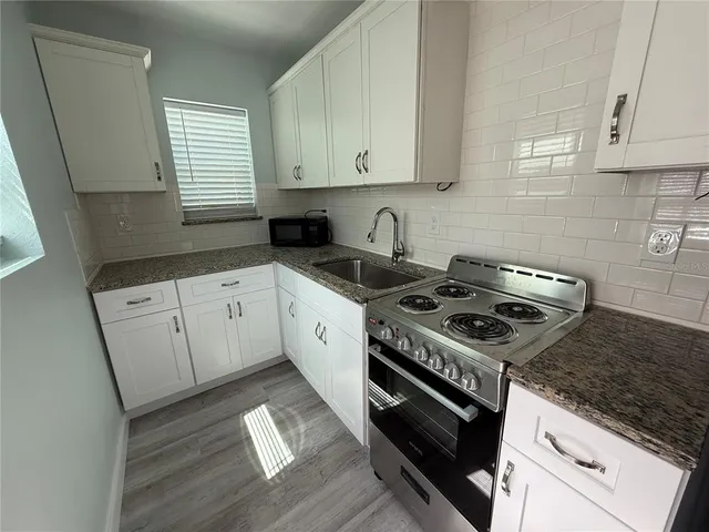 a kitchen with granite countertop a stove sink and cabinets