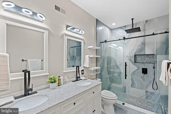 a bathroom with a granite countertop sink a toilet a mirror and shower