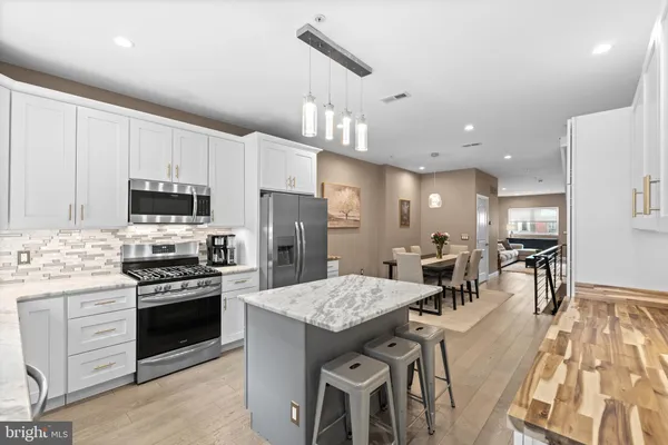 a kitchen with stainless steel appliances kitchen island granite countertop a stove a sink a oven a dining table and chairs