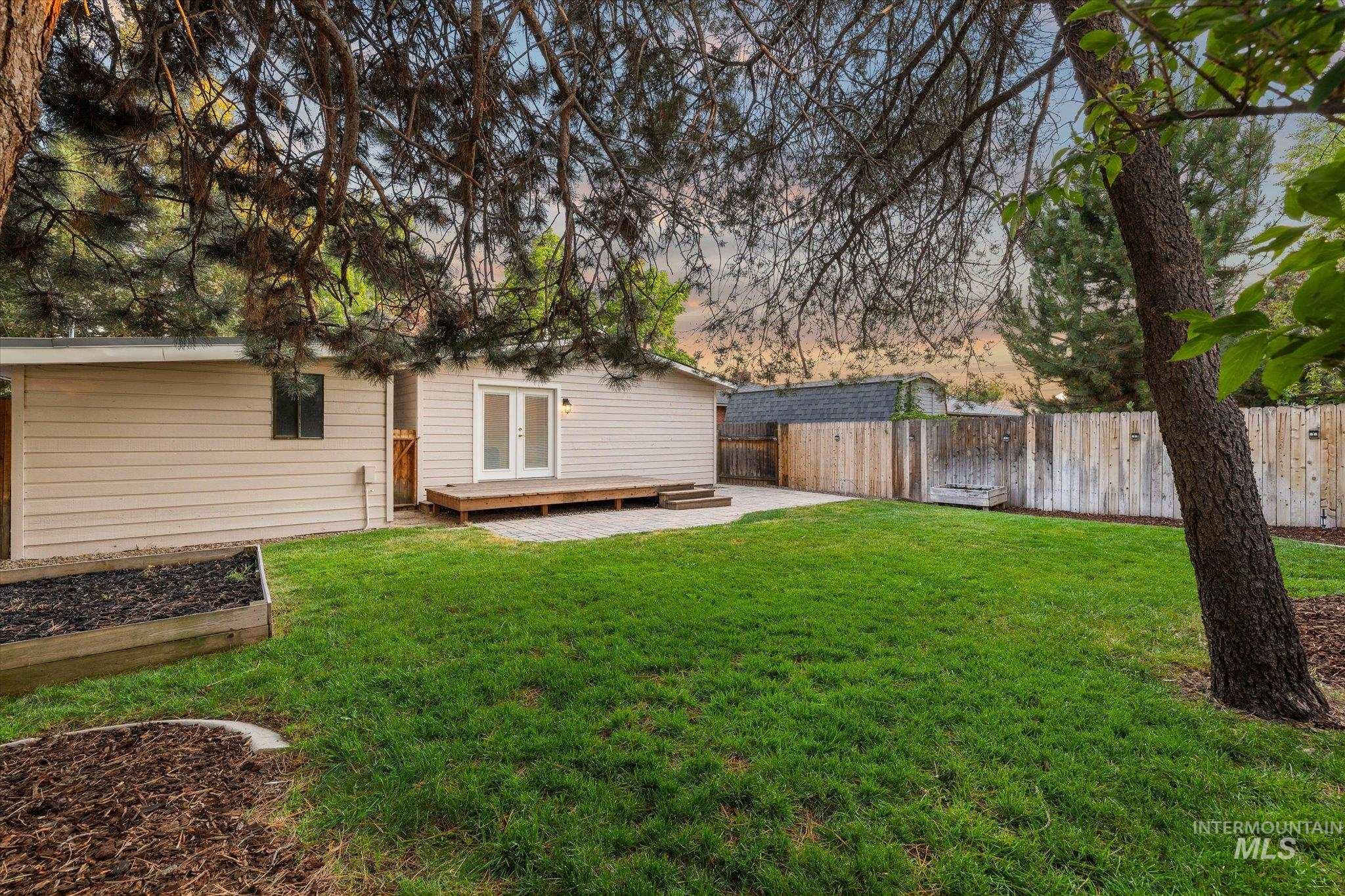 2302 Pendleton Street Boise, ID 83705 - Photo 31 of 35 Expansive grassy lawn with a wood plank deck, double glass doors, and a raised garden bed