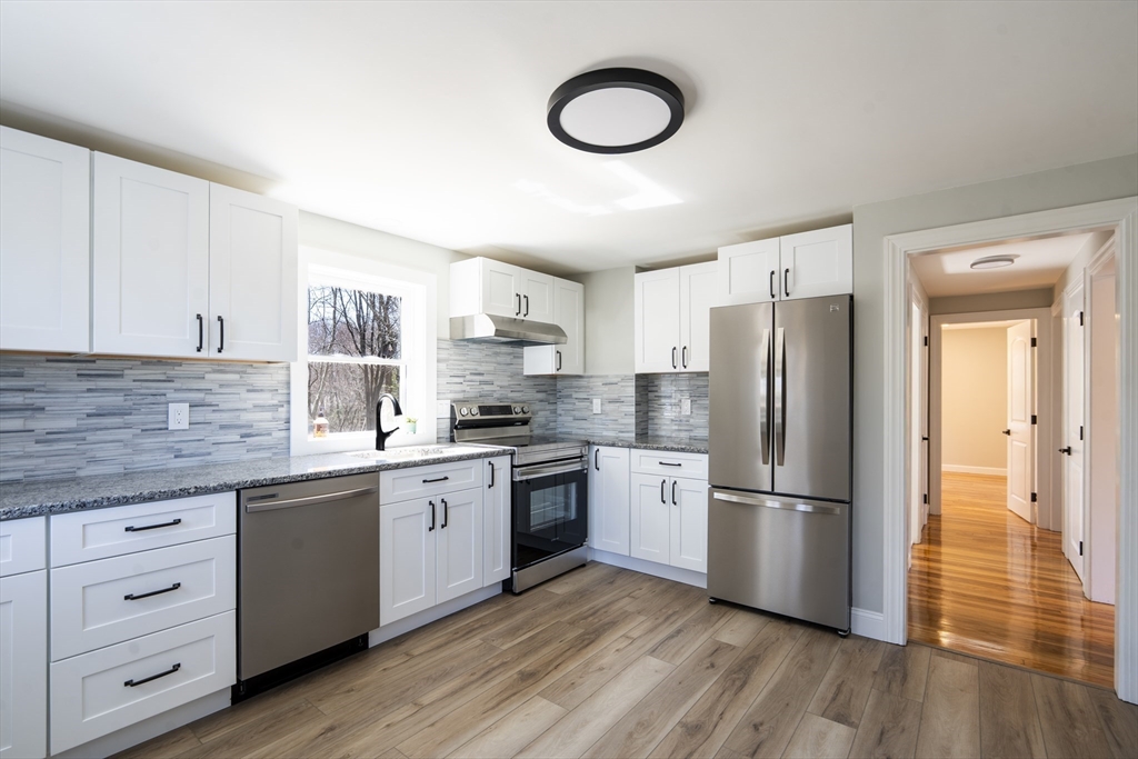 1049 Pleasant Street Canton, MA 02021 - Photo 4 of 34 a kitchen with white cabinets a sink dishwasher a refrigerator and a stove with wooden floor