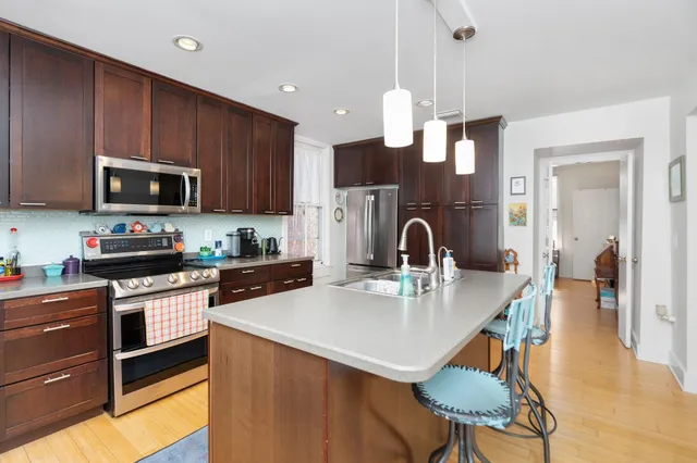 a kitchen with stainless steel appliances a stove a sink a microwave a refrigerator and cabinets