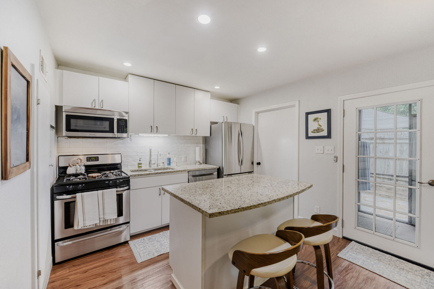 1912 Lightsey Road, Unit 6 Austin, TX 78704 - Photo 6 of 27 a kitchen with stainless steel appliances granite countertop a stove a sink a microwave a refrigerator and white cabinets with wooden floor