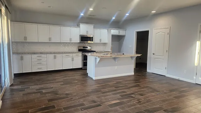 a kitchen with granite countertop white cabinets and stainless steel appliances