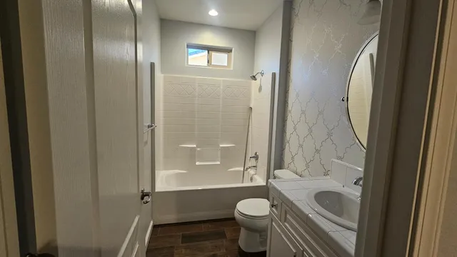 a bathroom with a granite countertop toilet a sink and a mirror