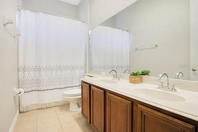a bathroom with a double vanity sink toilet and a mirror