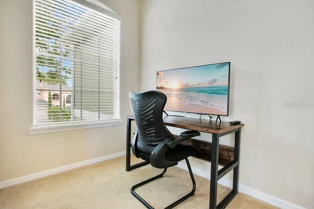a view of a workspace with furniture and a window