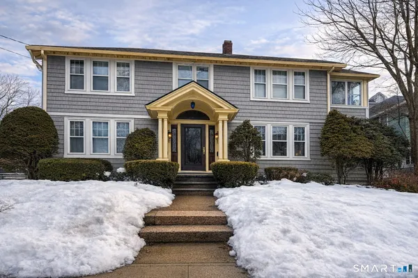 a front view of a house with a yard covered in snow
