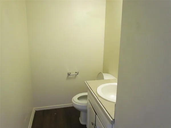 a white toilet sitting next to a white sink and a vanity