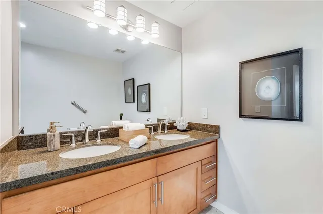 a bathroom with a granite countertop double vanity sink and a mirror