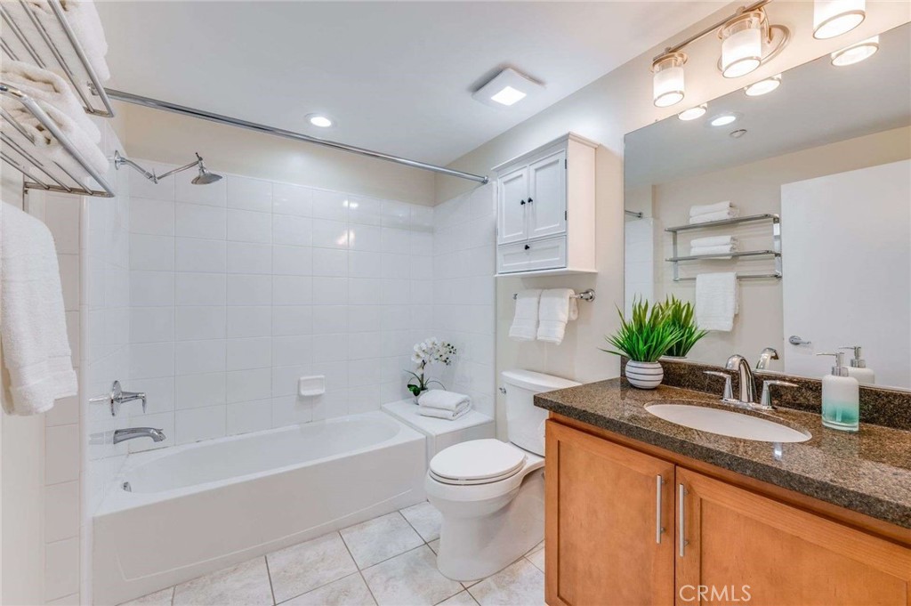 400 West Ocean Boulevard, Unit 206 Long Beach, CA 90802 - Photo 23 of 48 a bathroom with a granite countertop sink a toilet a mirror a bathtub and shower