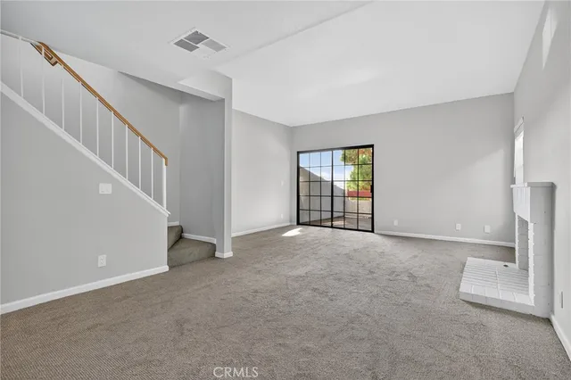 a view of an empty room with a fireplace and a window