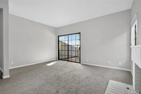 an empty room with windows and fireplace