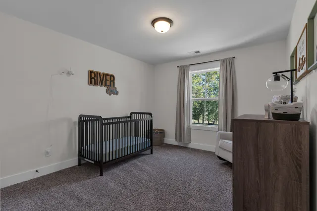 a view of a bedroom with baby crib and lounge chair