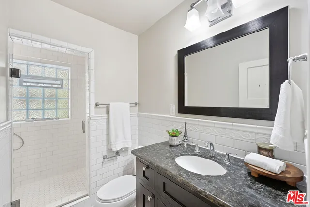 a bathroom with a granite countertop sink toilet a mirror and shower