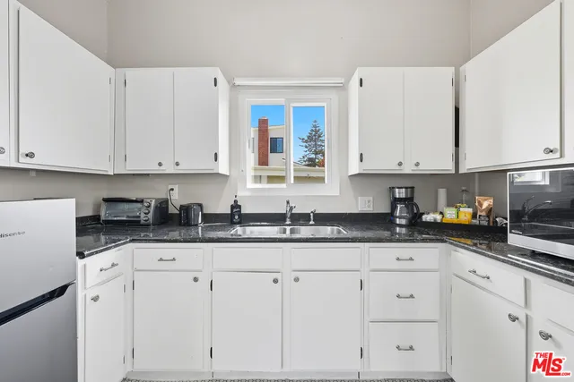 a kitchen with granite countertop white cabinets and white appliances