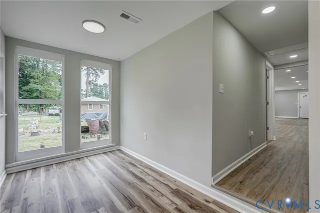 a view of empty room with wooden floor and fan