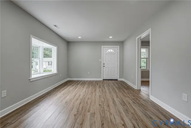 an empty room with wooden floor and windows