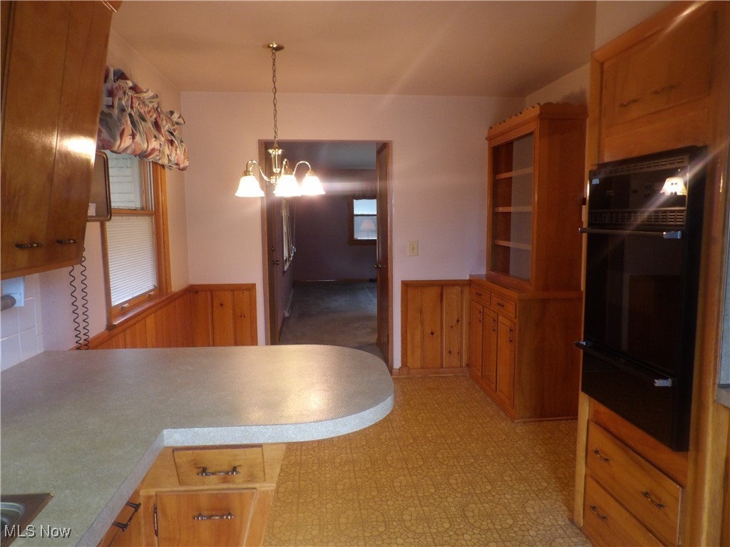 515 Hillman Road Akron, OH 44312 - Photo 5 of 17 Kitchen featuring a wainscoted wall, a warming drawer, black oven, hanging light fixtures, and wood walls