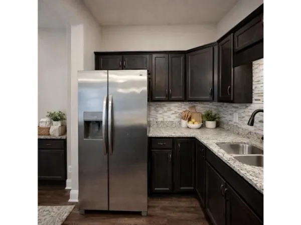 a kitchen with granite countertop a refrigerator and a sink