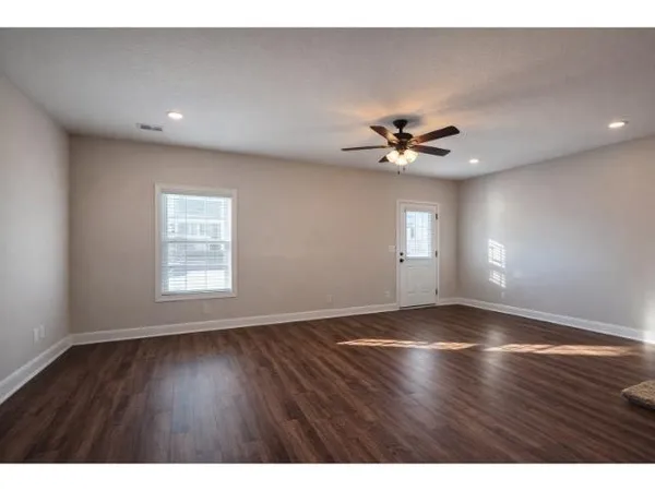 a view of an empty room with window and wooden floor