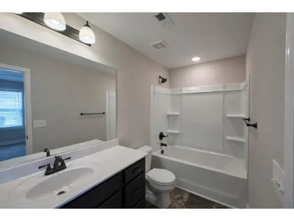 a bathroom with a sink a toilet a mirror and shower